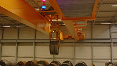 a large overhead bridge crane transports a heavy steel coil through an automated warehouse