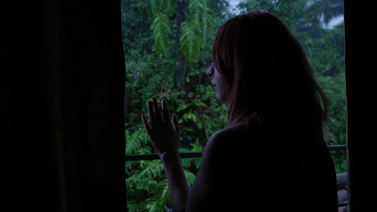 걱정 된 젊은 여성 이 창문 을 통해 밖 을 바라보는 장면
