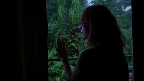 shot of a worried young woman looking outside through the window