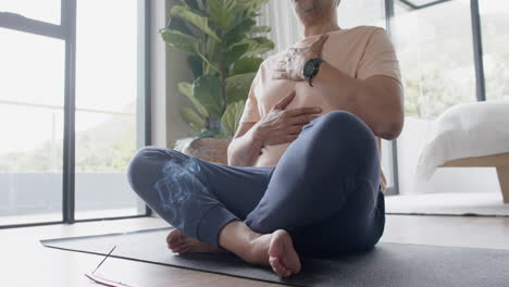 senior biracial man practicing yoga meditation at home