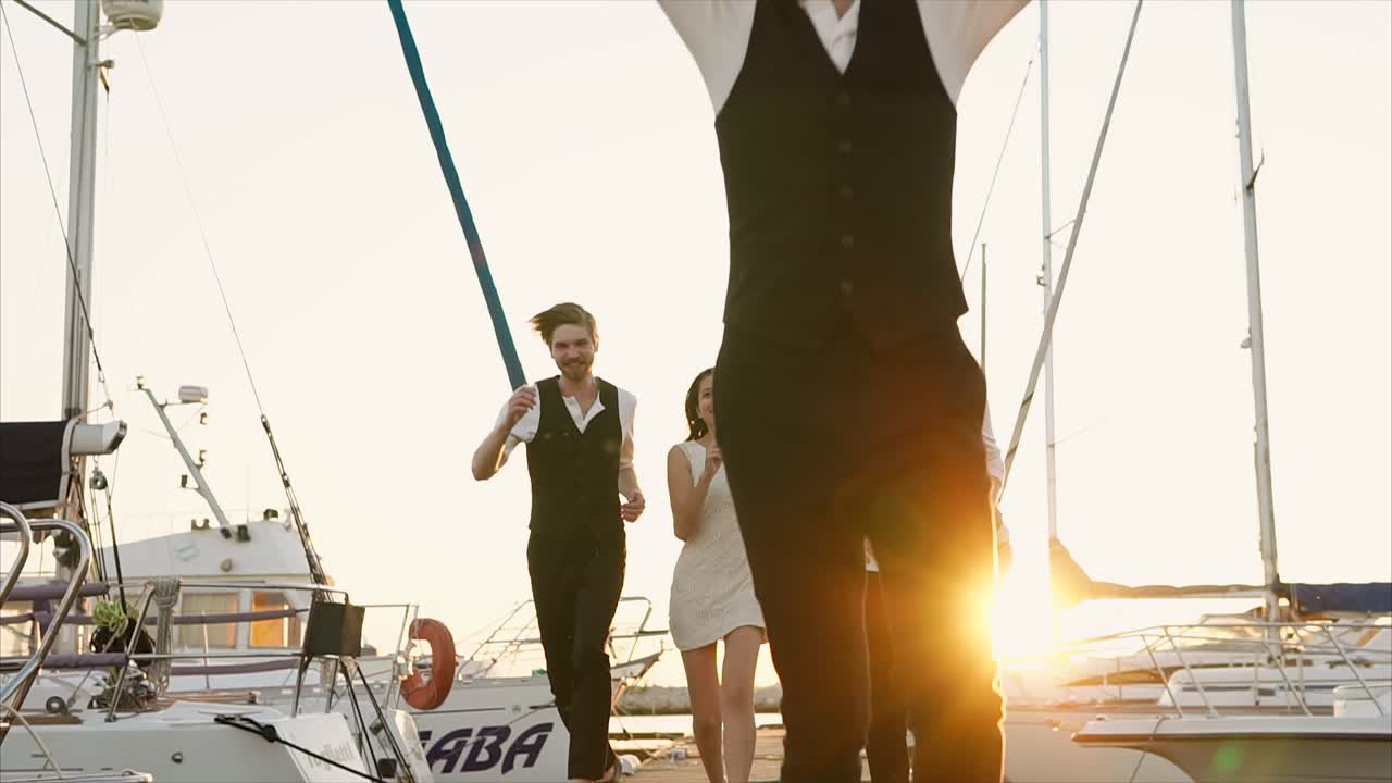 Group of friends dancing and celebrating on a pier at sunset