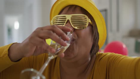 Happy-african-american-senior-woman-drinking-champagne-and-laughing-making-new-year's-eve-video-call