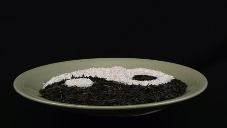 Plato-De-Arroz-Con-Diseño-Yin-Yang-Gira-Sobre-Fondo-Negro