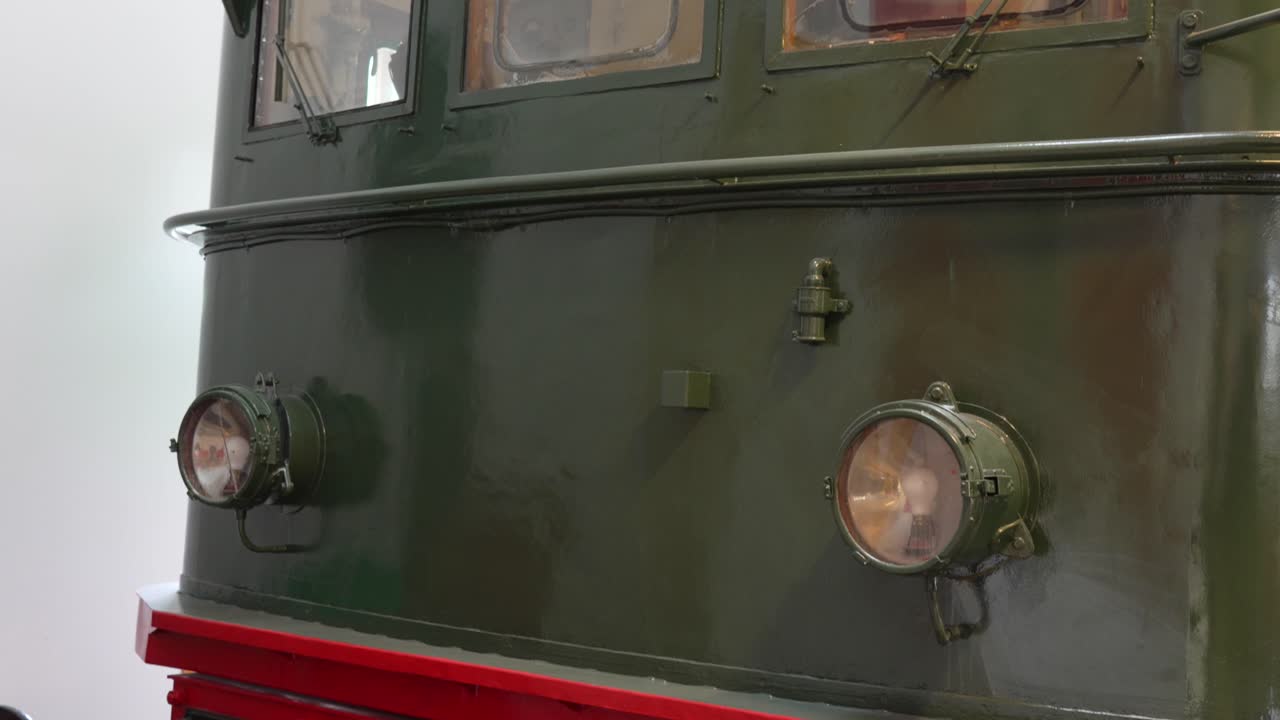 Camera pan down inside Flåm Railway Museum, Norway, revealing the front of a vintage green locomotive and its preserved industrial detailing