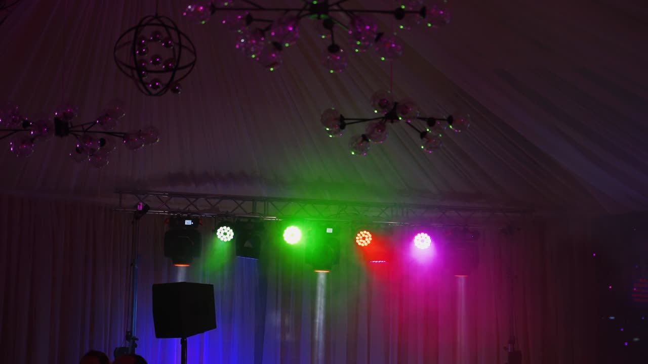 Professional lighting equipment on stage. Bright lasers and light rays emanating from central scene on musical dance show.