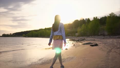 mujer caminando por una playa al atardecer
