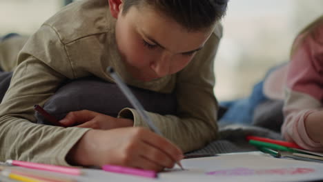 Cute-boy-coloring-picture-with-pencils.-Brother-drawing-next-to-sister-indoors.