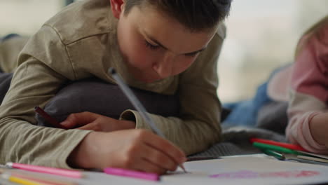 hermoso niño coloreando imágenes con lápices. hermano dibujando al lado de su hermana en el interior.