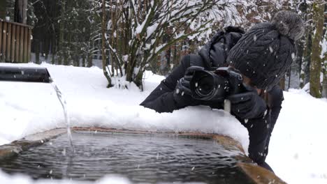 Mujer-Tomando-Fotos-De-Agua-Que-Fluye-Durante-La-Temporada-De-Invierno-Y-Nevadas