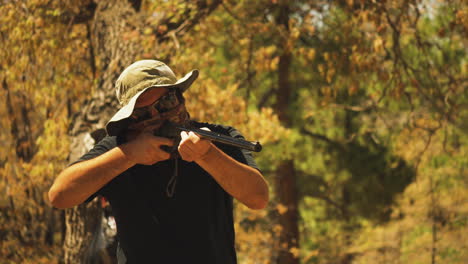 Primer-Plano-De-Un-Hombre-Disparando-Una-Pistola-De-Aire-Comprimido-Y-Recargando-Mientras-Dispara-Latas-En-Un-Campamento