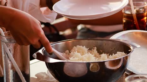 hands serving rice onto a plate