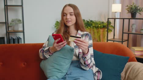 mujer sentada en casa usando tarjeta de crédito bancaria y teléfono inteligente mientras transfiere dinero a compras en línea