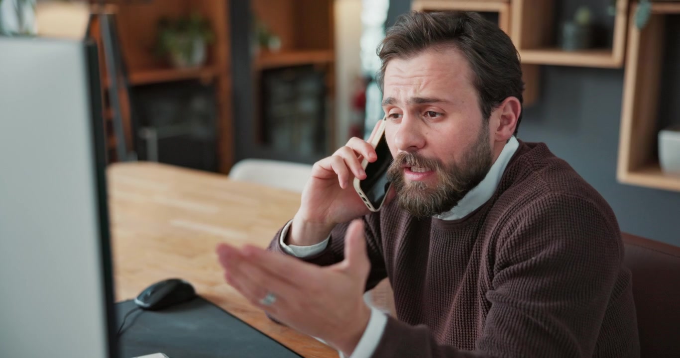 Bearded Man Having a Frustrated Phone Conversation in an Office