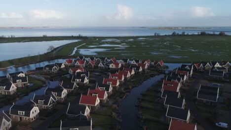 aerial wide of a small quiet dutch holiday park with countryside and ocean in the background during sunset