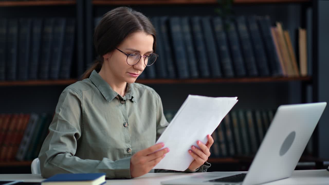 Modern business woman working with paper document and laptop at library desk