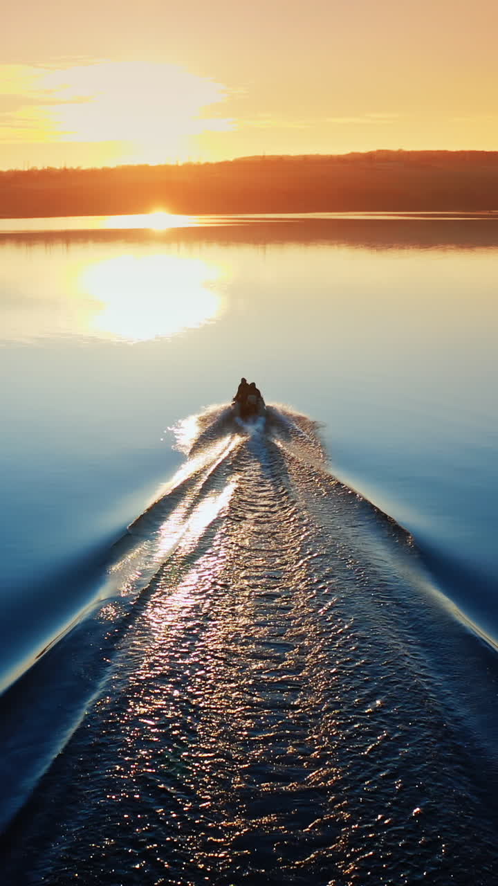 Motor boat floating on the river at sunset. Beautiful aerial view on the calm blue water in the evening. Boat moves along the river. Vertical video