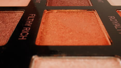 close-up of an eyeshadow palette with various shades of orange, pink, and brown