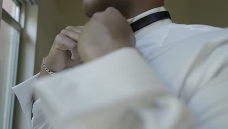 groom tying bow tie