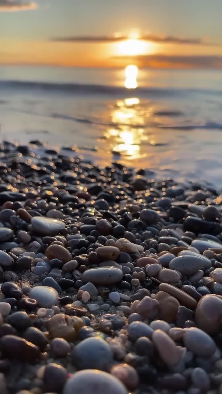 Video ravvicinato di ciottoli su una spiaggia al tramonto, che cattura la serena linea dell'orizzonte e la luce dorata, Live