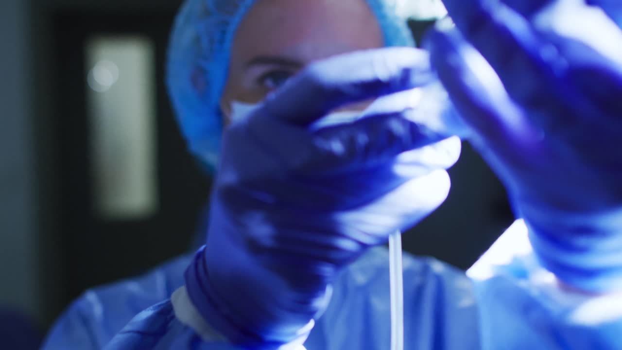 Caucasian female doctor wearing face mask preparing patient's iv drip in operating theatre