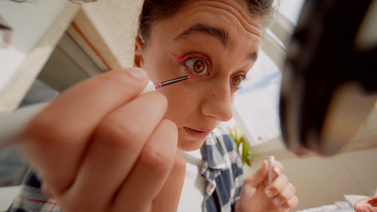 Close-up of Young Woman Applying Vibrant Pink Eyeliner