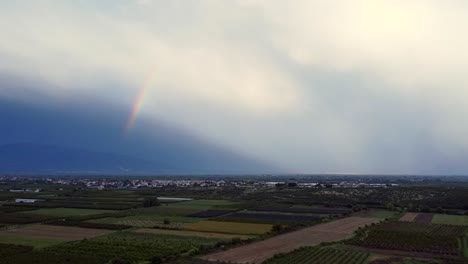 Bunter-Regenbogen-Hinter-Bewölktem-Himmel-über-Ländlichem-Dorf