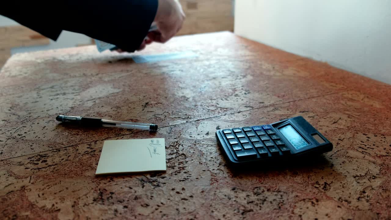 Un uomo conta i soldi appoggiandoli sul tavolo. Mani in primo piano