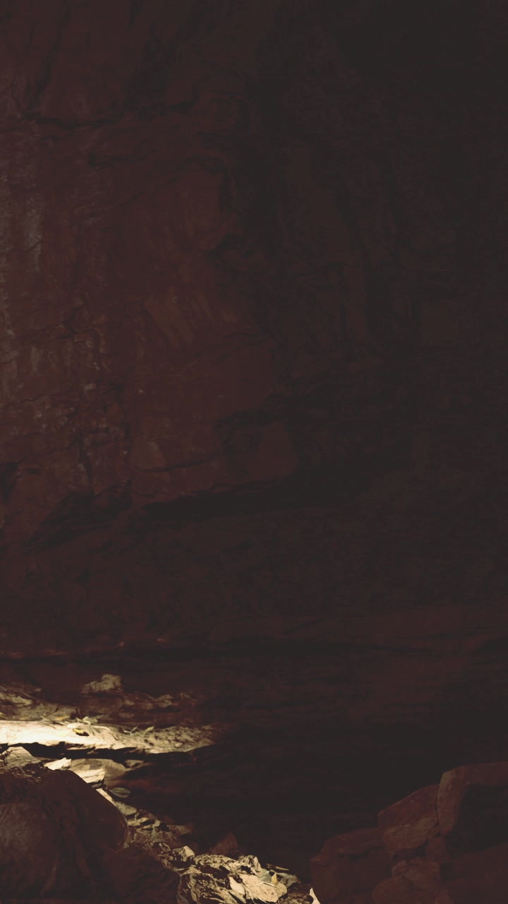 Exploring a dark cave with rocks shadows and limited light during daytime