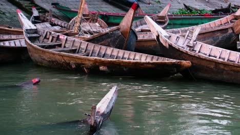 Traditional-wooden-canoe-boat-on-polluted-river-at-wharf-in-Dhaka,-Bangladesh