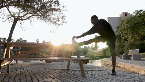 young black man stretching legs before running outdoors