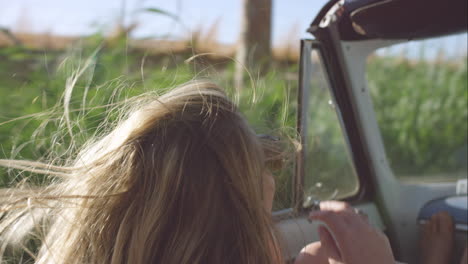 Young-wild-free-woman-in-convertible-car-on-a-road-trip-in-the-wind-slow-motion