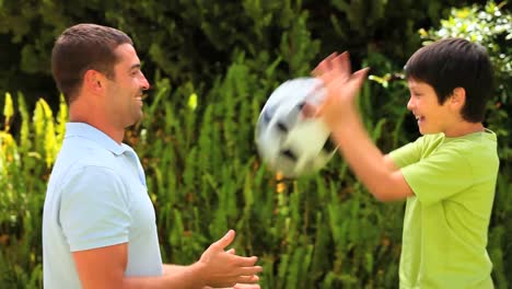 Young-boy-and-his-father-playing-with-a-football-