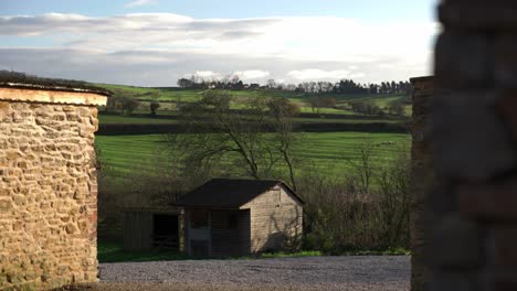 tight peeking view of fields and rolling green hills of north yorkshire from a farmers yard on a cold but sunny winter day