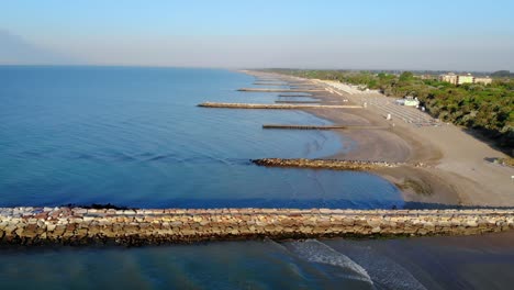 Paisaje-Marino-De-Drones,-Costa-De-Agua-Azul,-Entradas,-Embarcadero,-Playa,-Vista-De-Largo-Alcance,-Caorle,-Italia