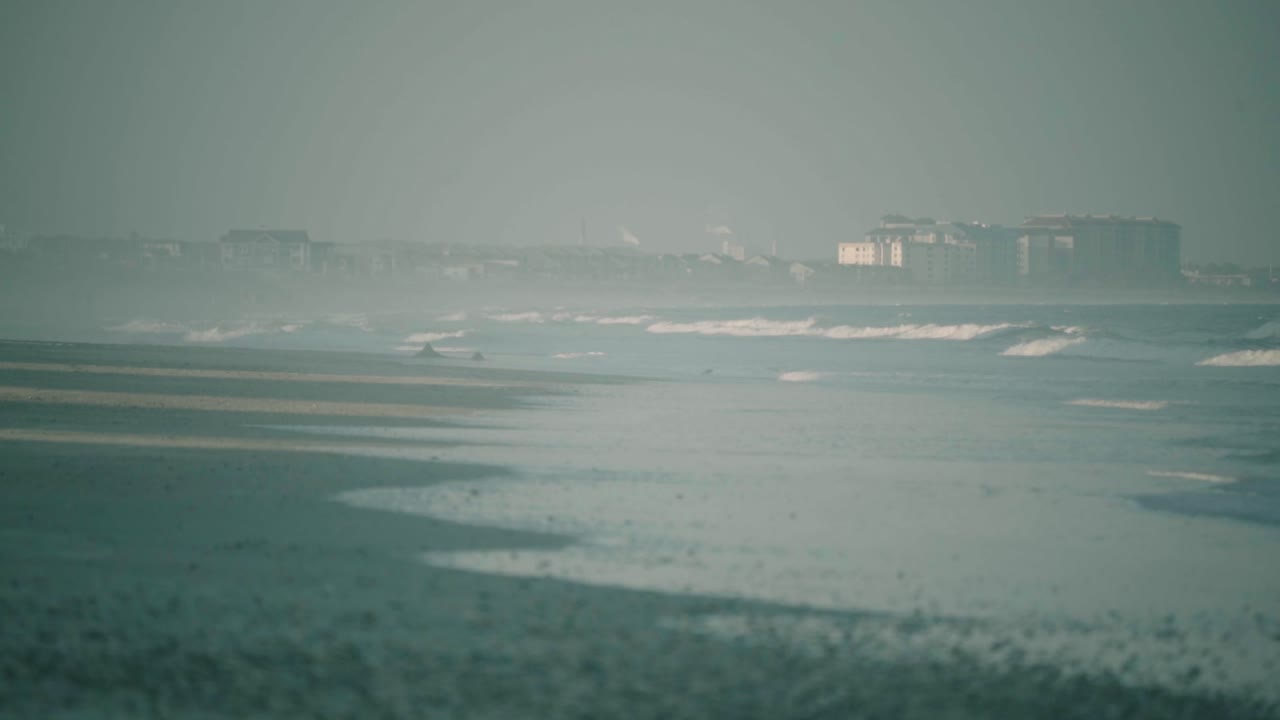 안개 낀 흐린 아침에 해변 해안으로 굴러가는 잔잔한 조수 파도