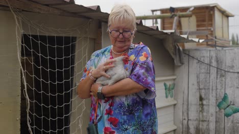 senior woman holding a chicken in her backyard