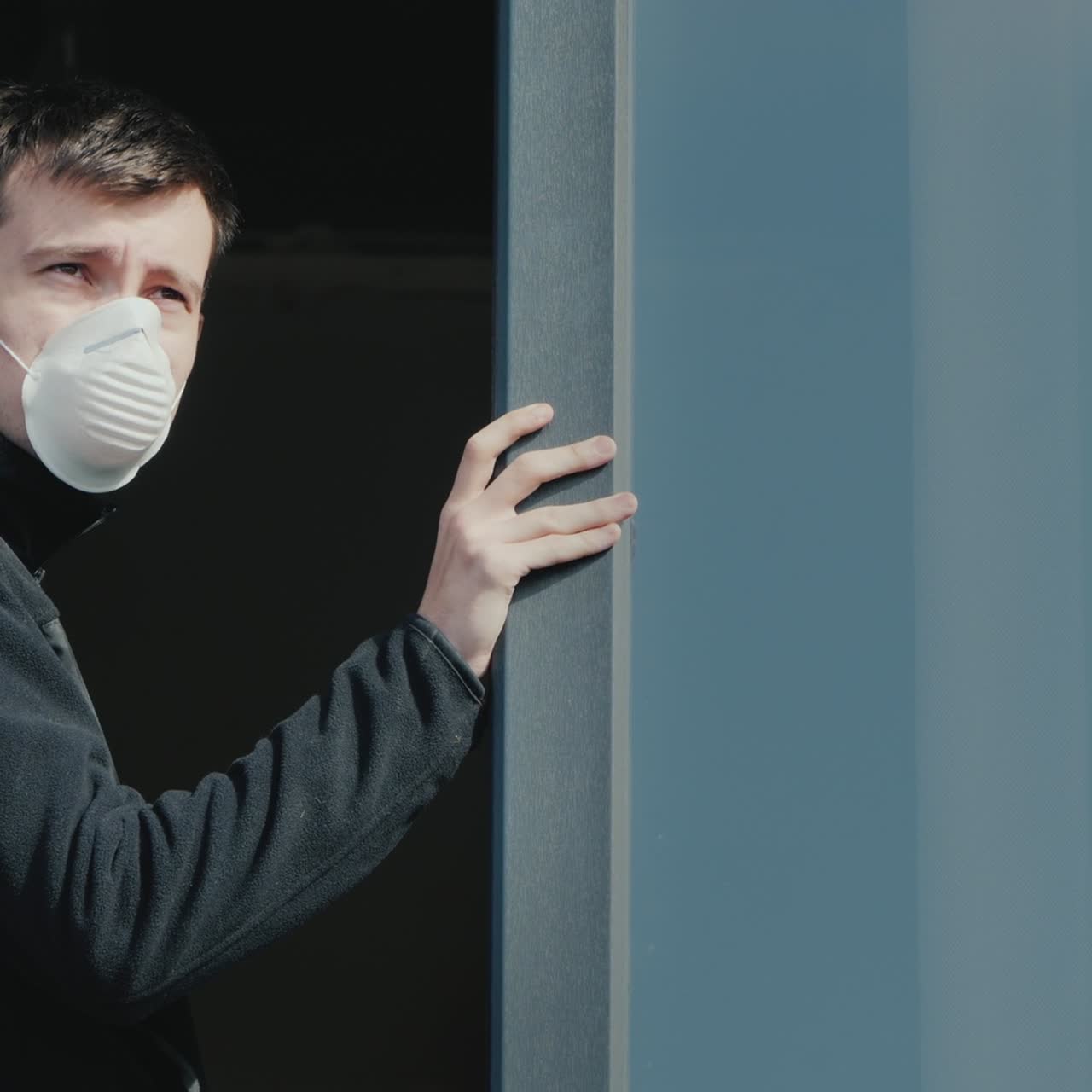 가면을 쓴 슬픈 남자가 창밖을 내다본다