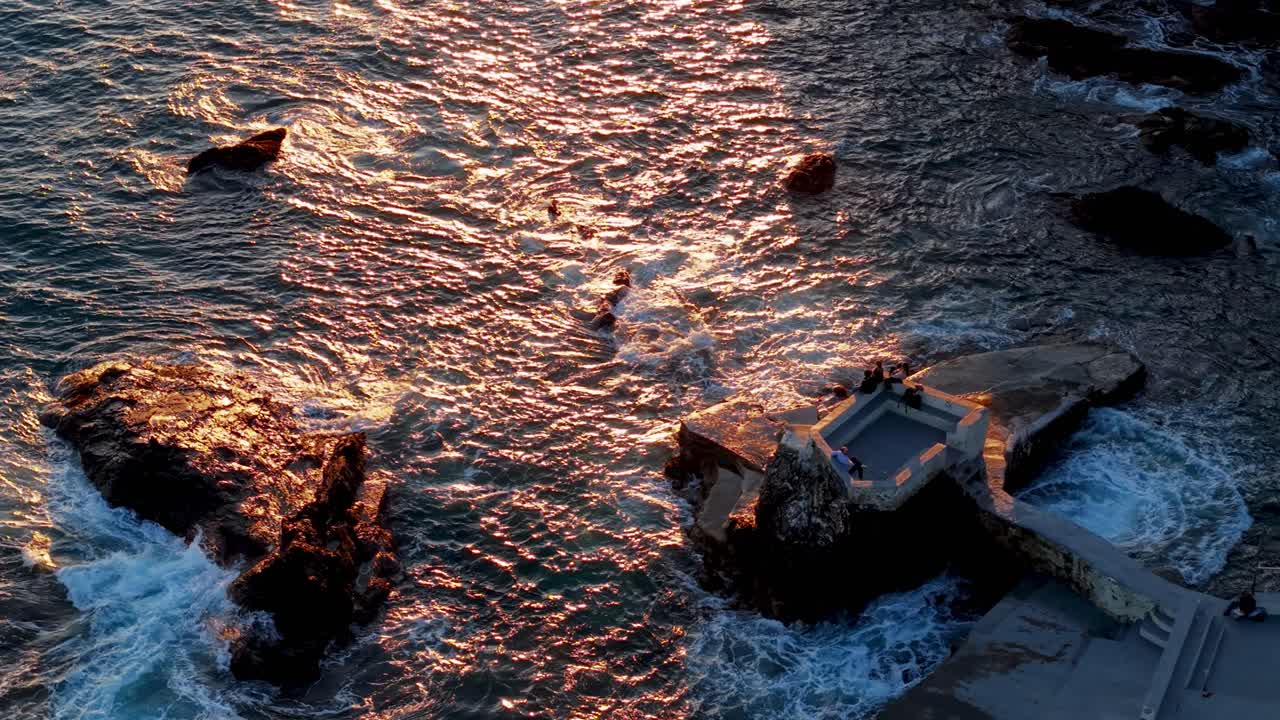 Sunset view of the rocky coastline in Genoa, Italy with the ocean waves gently hitting rocks