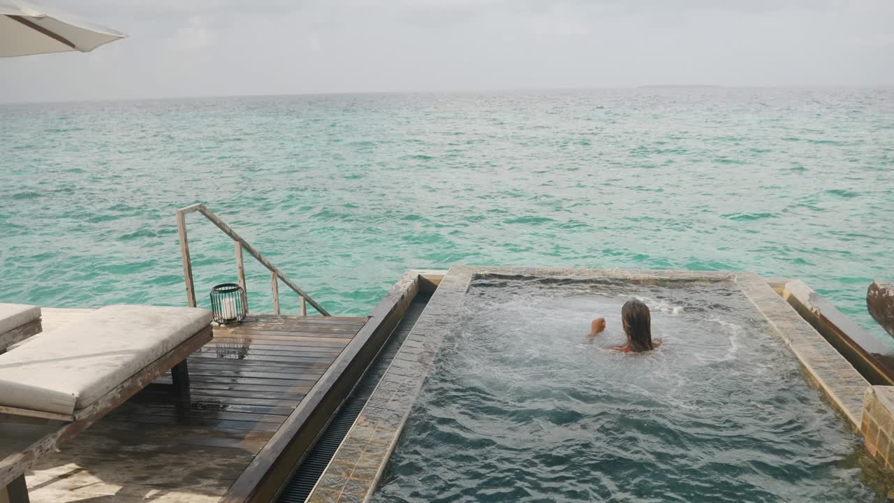 hombre saltando en la piscina infinita en vacaciones, bungalow sobre el agua, isla de las maldivas