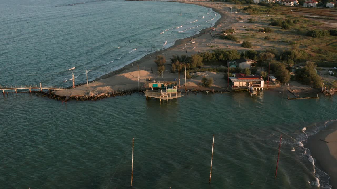 toma aérea de los valles cerca de ravenna donde el río desemboca en el mar con las típicas cabañas de pescadores al atardecer