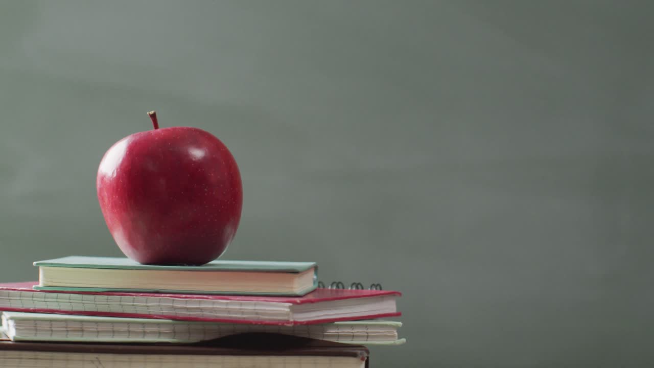 видео книг и яблока на деревянном столе над математическими формулами на доске