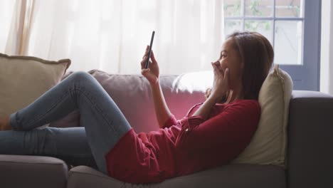 mixed race woman using a smartphone. social distancing and self isolation in quarantine