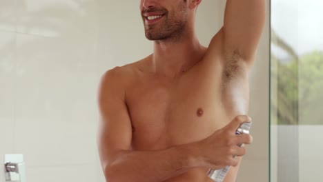 handsome man putting deodorant on his armpit