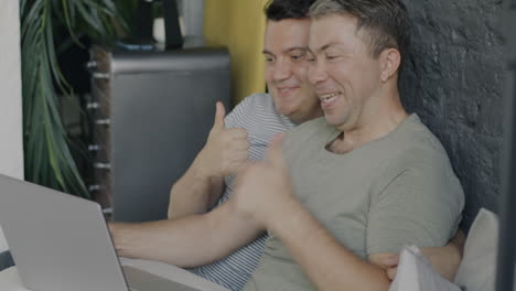 happy gay couple watching laptop