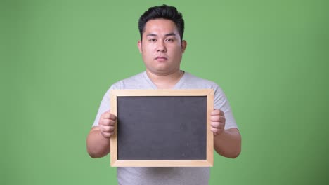 초록색 배경에 젊은 잘생긴 과체중 아시아인