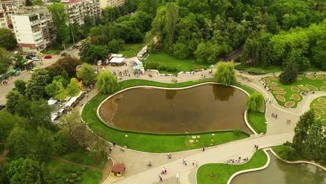 drone aéreo que se eleva sobre el lago del parque de la ciudad con gente caminando