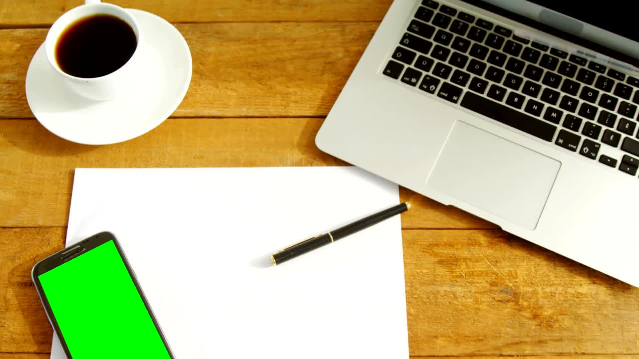 Laptop, blank paper, mobile phone, pen and coffee on table 4k