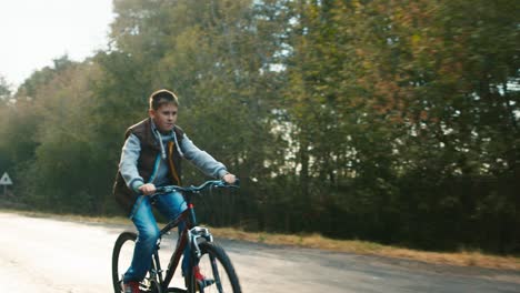 a teenager rides a bicycle on a country road