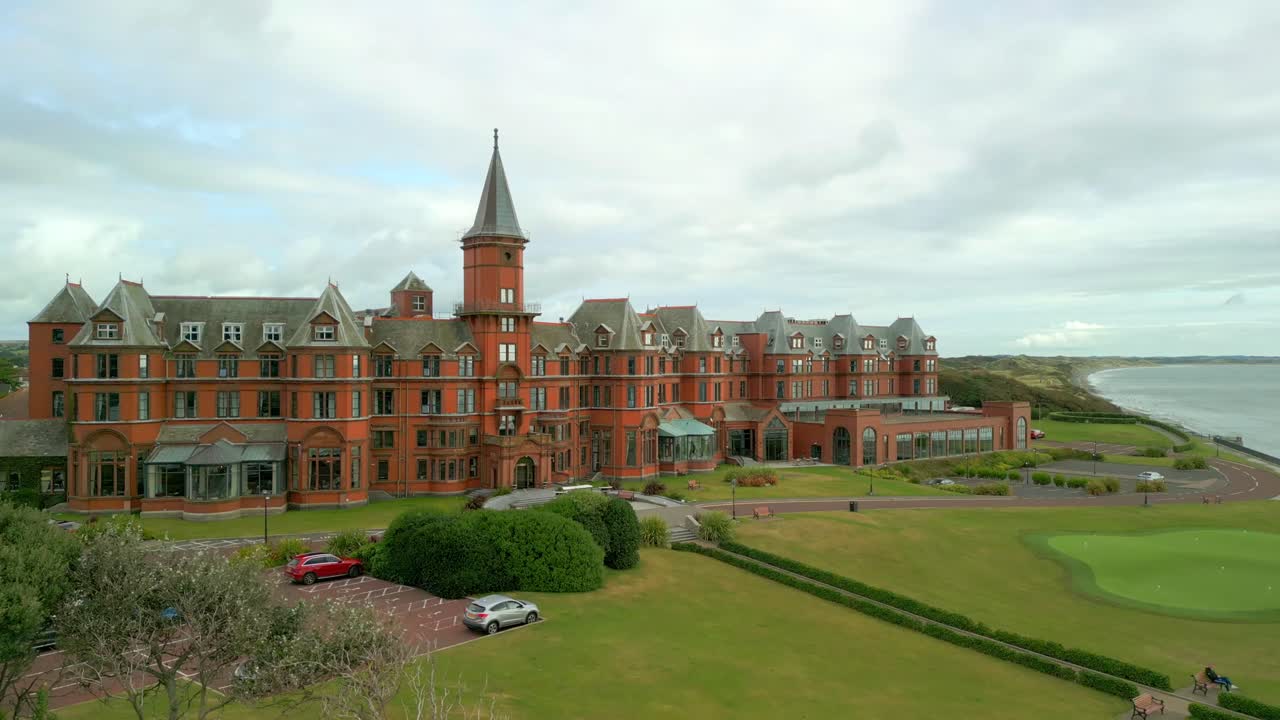 4K, 60FPS aerial video of the Slieve Donard Hotel in Newcastle, County Down in Northern Ireland. The camera reverses from a mid-shot to a wide