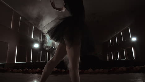 close-up shot of ballerina's legs. she dances on her pointe ballet shoes. she's wearing black tutu dress. shot in a bright and sunny studio. in slow motion.